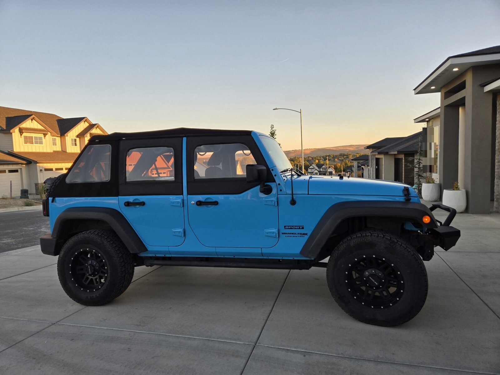 The same Jeep Wrangler Unlimited today, lifted on 35-inch tyres with a steel front bumper, photographed from the passenger side.
